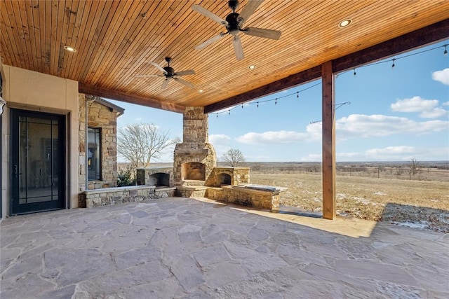 view of patio / terrace with ceiling fan, a rural view, and an outdoor stone fireplace