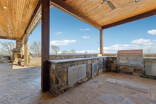 view of patio featuring ceiling fan, an outdoor kitchen, a fireplace, and area for grilling