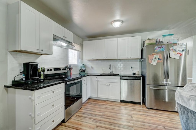 kitchen featuring sink, white cabinetry, light hardwood / wood-style flooring, dark stone countertops, and appliances with stainless steel finishes