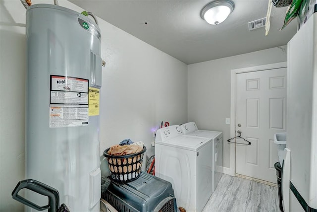 washroom with electric water heater, washer and clothes dryer, and light hardwood / wood-style floors