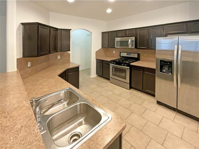 kitchen featuring tasteful backsplash, appliances with stainless steel finishes, sink, and dark brown cabinetry