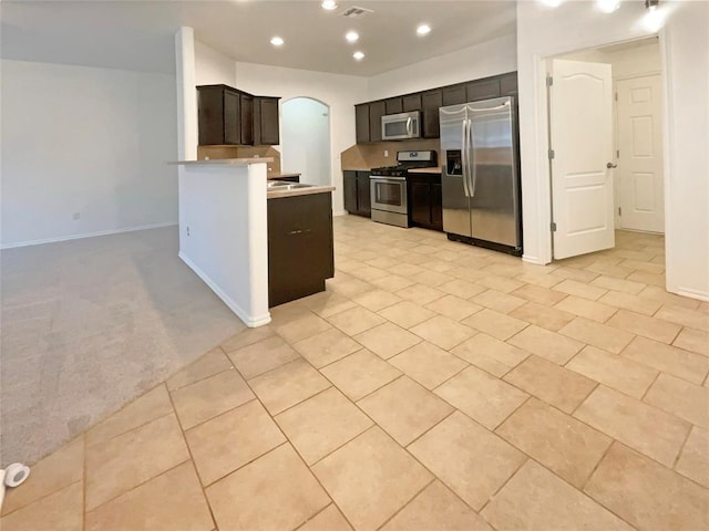 kitchen with light colored carpet, kitchen peninsula, and appliances with stainless steel finishes