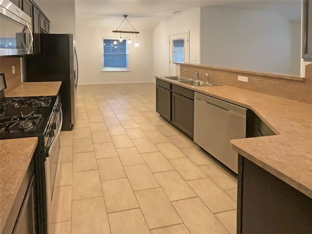 kitchen featuring pendant lighting, sink, stainless steel appliances, tasteful backsplash, and light tile patterned flooring