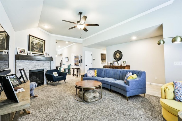 living room with lofted ceiling, crown molding, a stone fireplace, and ceiling fan