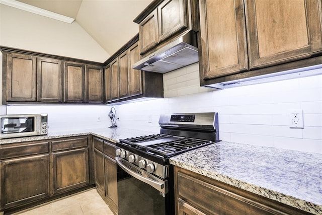 kitchen with lofted ceiling, stainless steel appliances, light stone counters, light tile patterned flooring, and decorative backsplash