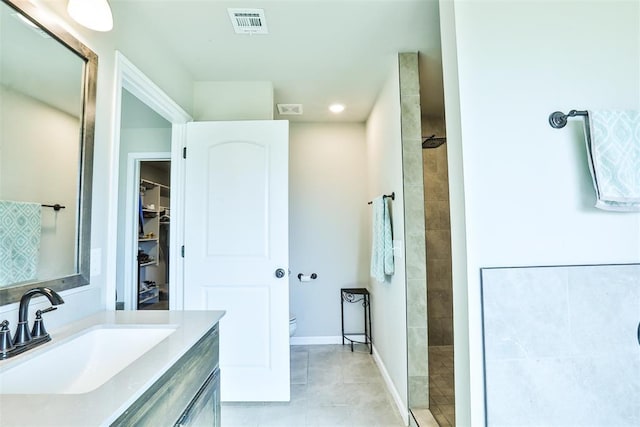 bathroom with vanity, tiled shower, and toilet