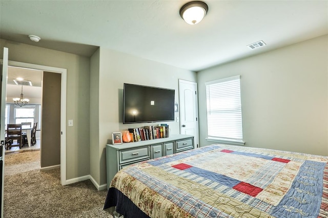 carpeted bedroom featuring an inviting chandelier