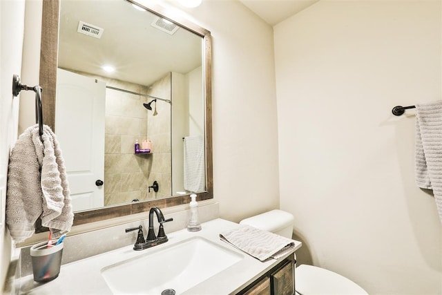 bathroom with vanity, toilet, and tiled shower