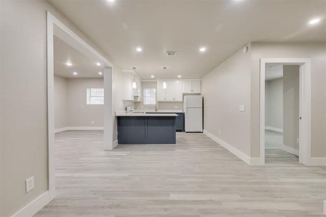 kitchen with white cabinetry, white refrigerator, hanging light fixtures, light hardwood / wood-style floors, and kitchen peninsula