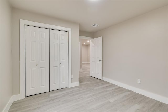 unfurnished bedroom featuring light hardwood / wood-style flooring and a closet