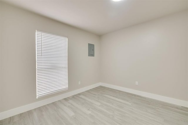 spare room featuring electric panel and light hardwood / wood-style floors