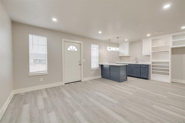 kitchen with pendant lighting, sink, a wealth of natural light, light hardwood / wood-style floors, and white cabinets