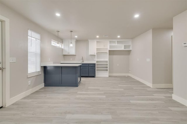 kitchen featuring sink, decorative light fixtures, light hardwood / wood-style flooring, and white cabinets