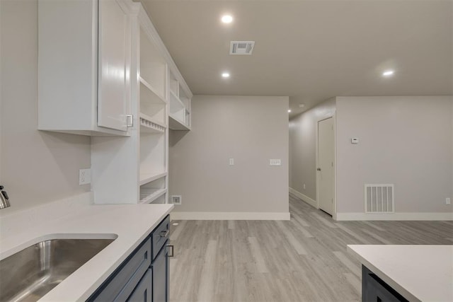 kitchen with white cabinetry, sink, and light hardwood / wood-style flooring