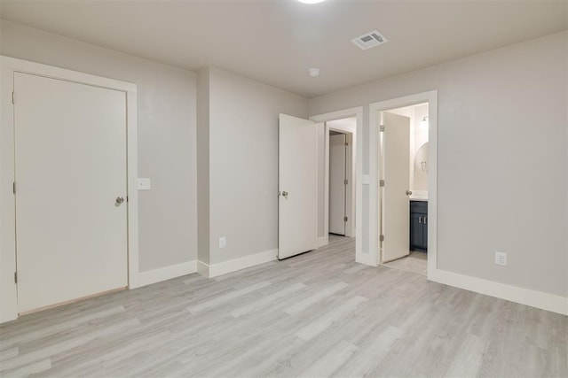 unfurnished bedroom featuring connected bathroom and light wood-type flooring