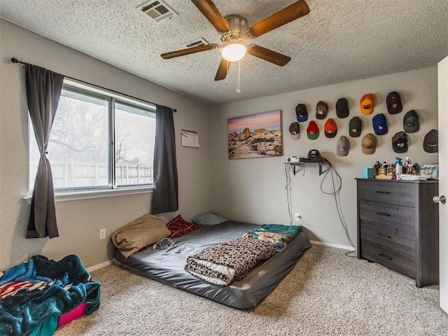 bedroom with ceiling fan, light carpet, and a textured ceiling