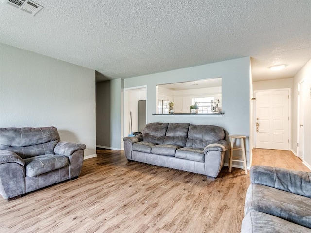 living room with a textured ceiling and light wood-type flooring