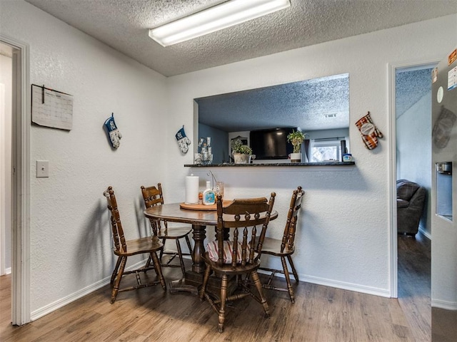 dining room with a textured ceiling and wood-type flooring