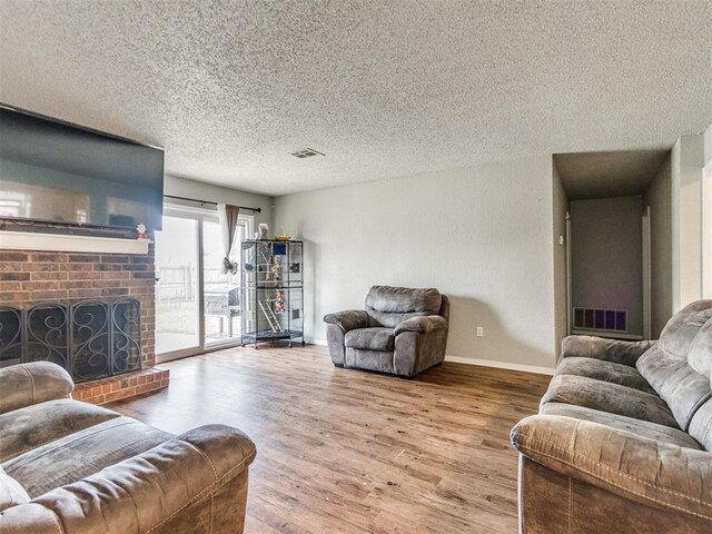 living room with hardwood / wood-style flooring, a textured ceiling, and a fireplace