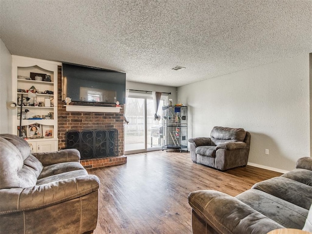 living room with a fireplace, built in features, a textured ceiling, and hardwood / wood-style floors