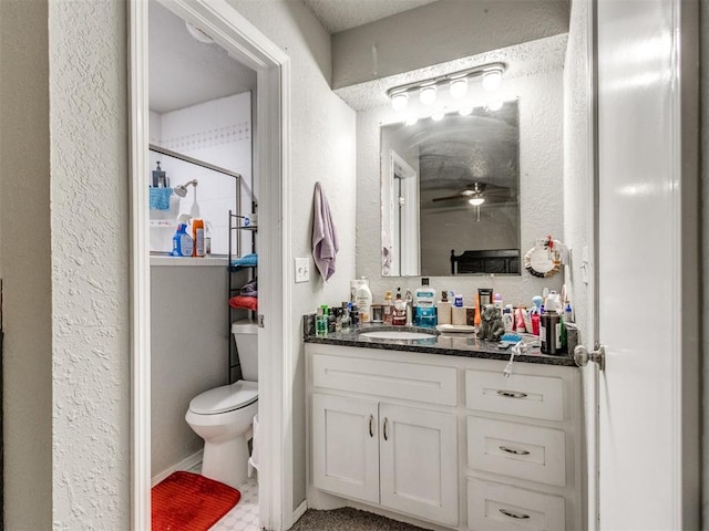 bathroom featuring ceiling fan, vanity, toilet, and a shower