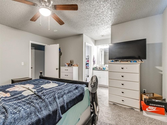 carpeted bedroom featuring ceiling fan, ensuite bath, and a textured ceiling