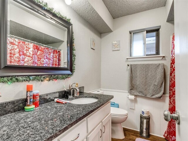 bathroom with a textured ceiling, toilet, vanity, and hardwood / wood-style flooring