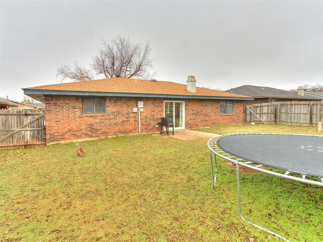 rear view of house featuring a patio, a yard, and a trampoline