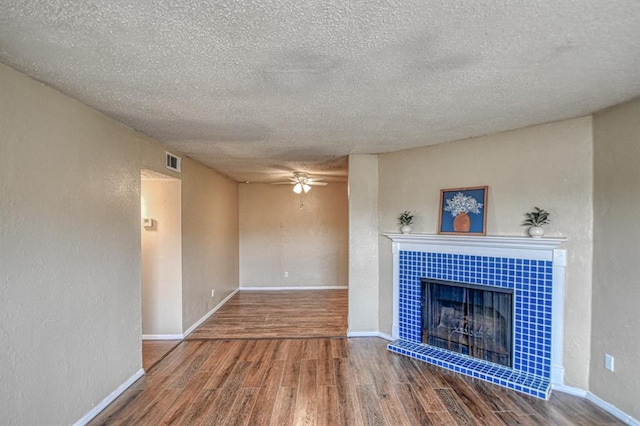 unfurnished living room with hardwood / wood-style flooring, a fireplace, a textured ceiling, and ceiling fan