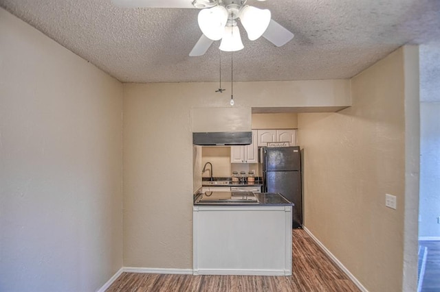 kitchen featuring black fridge, hardwood / wood-style flooring, sink, and white cabinets