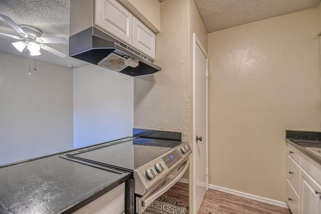 kitchen featuring stainless steel range with electric stovetop, a textured ceiling, and white cabinets