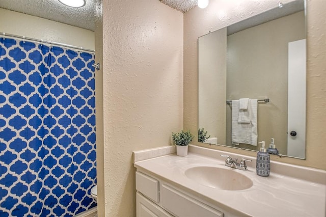 full bathroom featuring a textured ceiling, vanity, a shower with curtain, and a textured wall