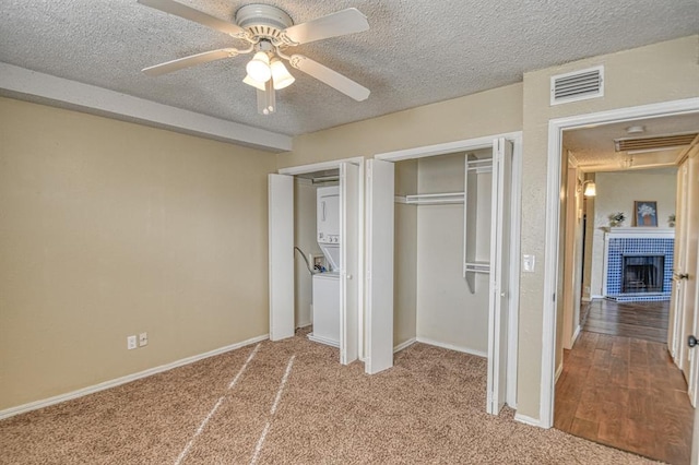 unfurnished bedroom featuring ceiling fan, light colored carpet, a brick fireplace, and a textured ceiling