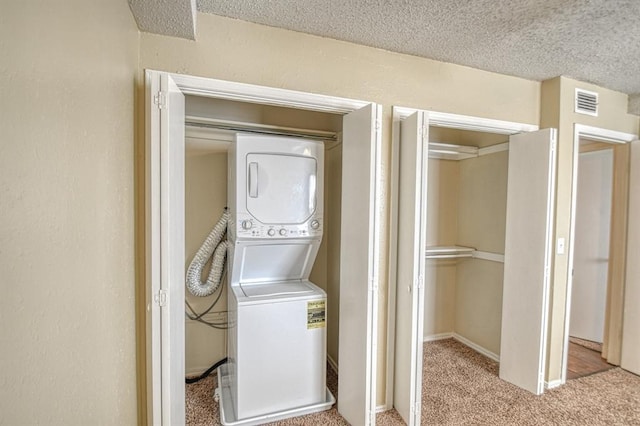 clothes washing area with light carpet, a textured ceiling, and stacked washing maching and dryer