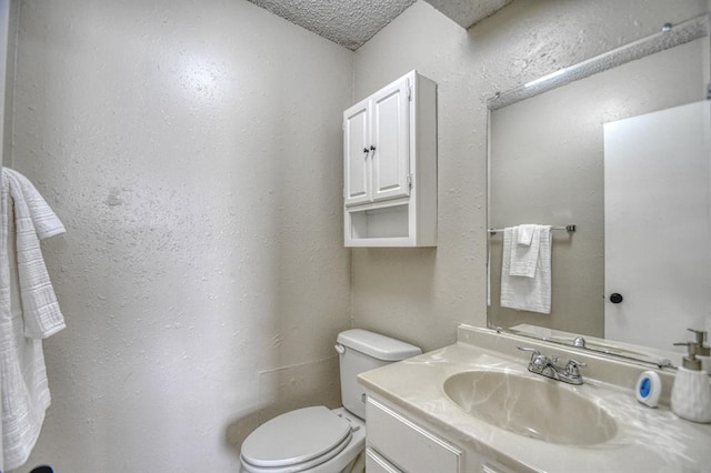 half bath featuring toilet, vanity, and a textured wall