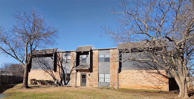 exterior space featuring brick siding, fence, and a lawn