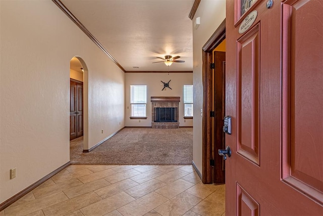 carpeted foyer entrance with crown molding, ceiling fan, and a brick fireplace