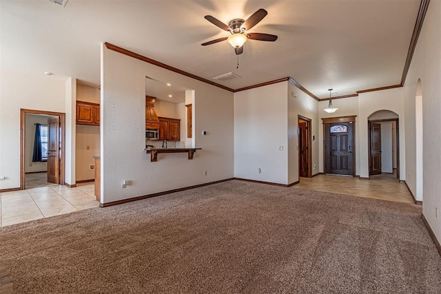 unfurnished living room featuring ornamental molding, light colored carpet, and ceiling fan