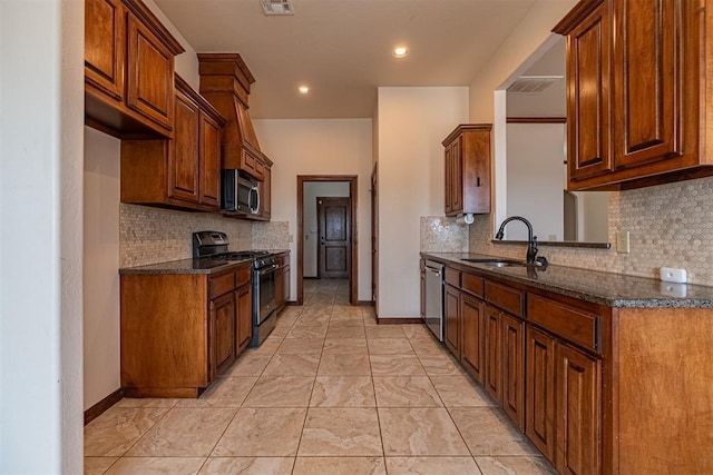 kitchen with tasteful backsplash, appliances with stainless steel finishes, sink, and dark stone countertops