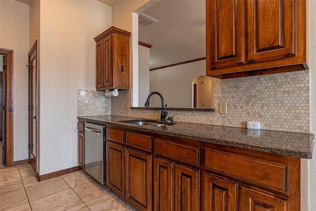 kitchen featuring sink, light tile patterned floors, backsplash, stainless steel dishwasher, and dark stone counters