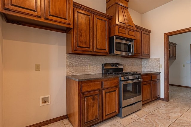 kitchen featuring appliances with stainless steel finishes, decorative backsplash, and dark stone counters