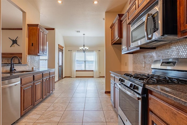 kitchen featuring pendant lighting, sink, dark stone countertops, a chandelier, and stainless steel appliances