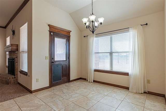 entrance foyer with a fireplace, ornamental molding, light tile patterned flooring, vaulted ceiling, and a chandelier