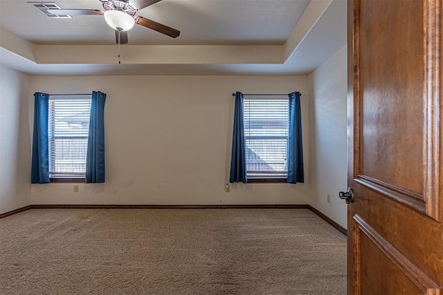 carpeted spare room featuring a raised ceiling and ceiling fan