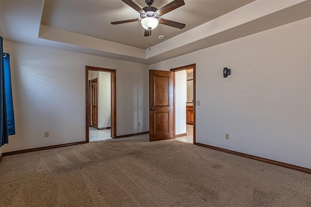 carpeted spare room featuring a raised ceiling and ceiling fan