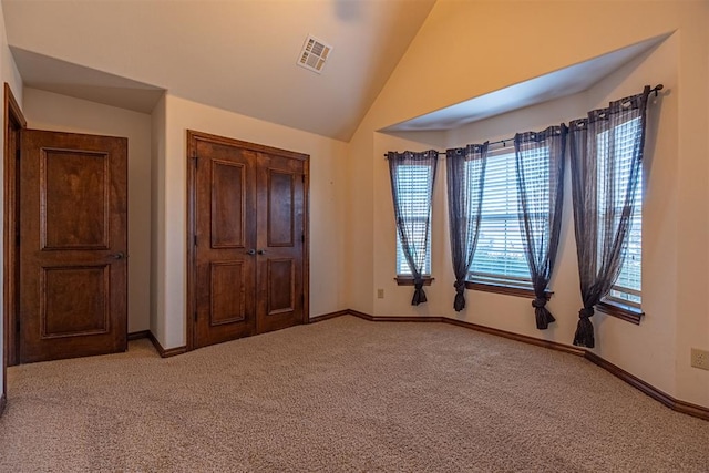 unfurnished bedroom featuring lofted ceiling and light colored carpet