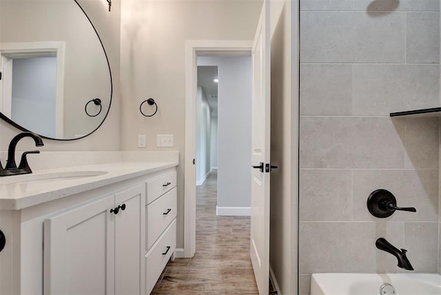 bathroom featuring hardwood / wood-style flooring, vanity, and tiled shower / bath combo