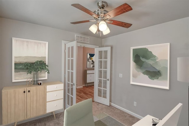 office area featuring french doors, ceiling fan, and light carpet