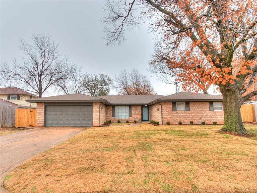 ranch-style house featuring a garage and a front lawn