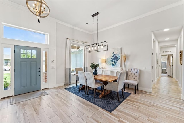 dining room with an inviting chandelier, a towering ceiling, a healthy amount of sunlight, and crown molding